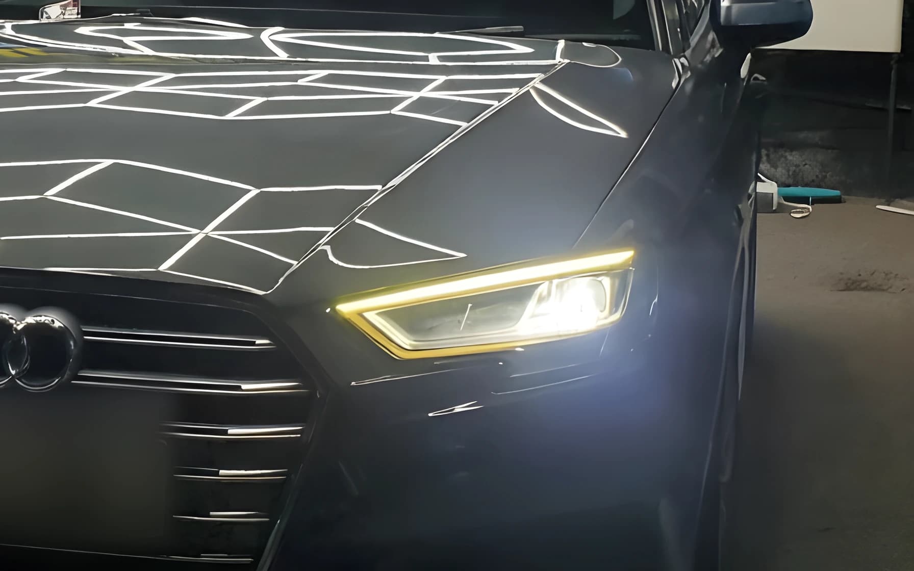 Close detail of the headlight and front wing of a dark saloon