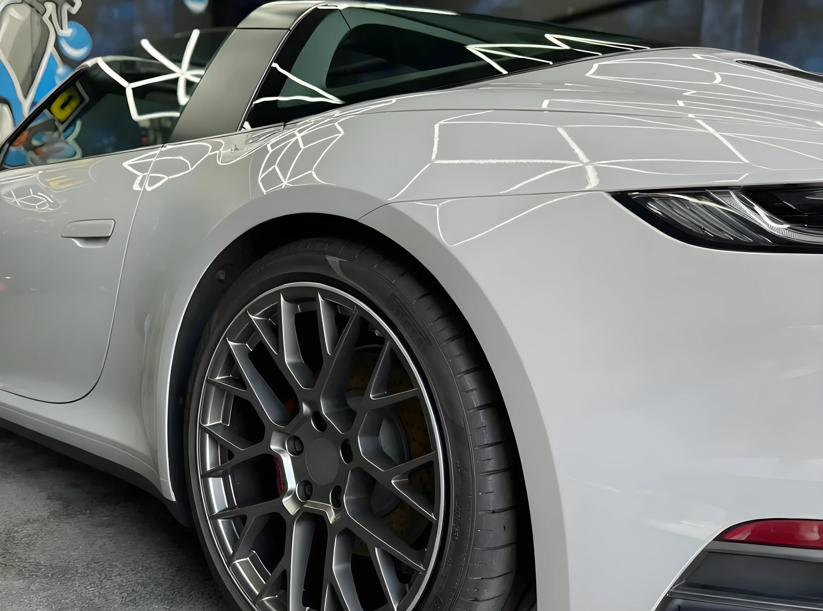 A silver sports car with corrected, reflective paintwork in the studio