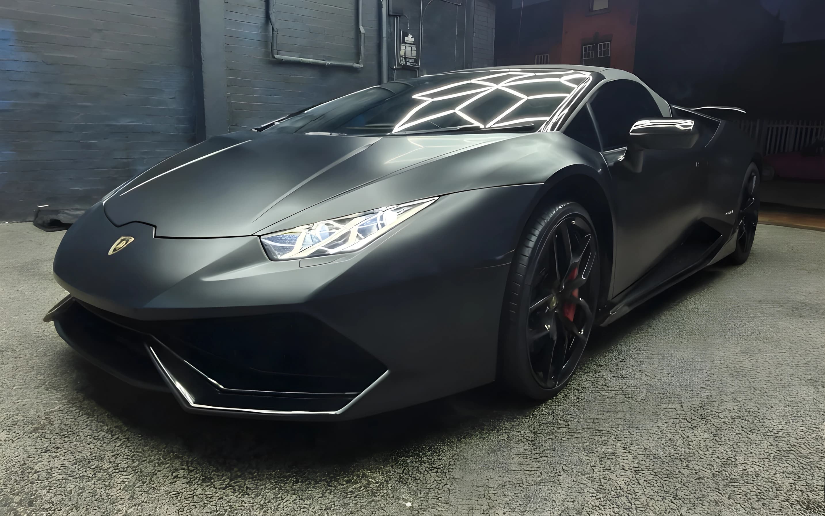 The front of a matte black supercar in the detailing bay